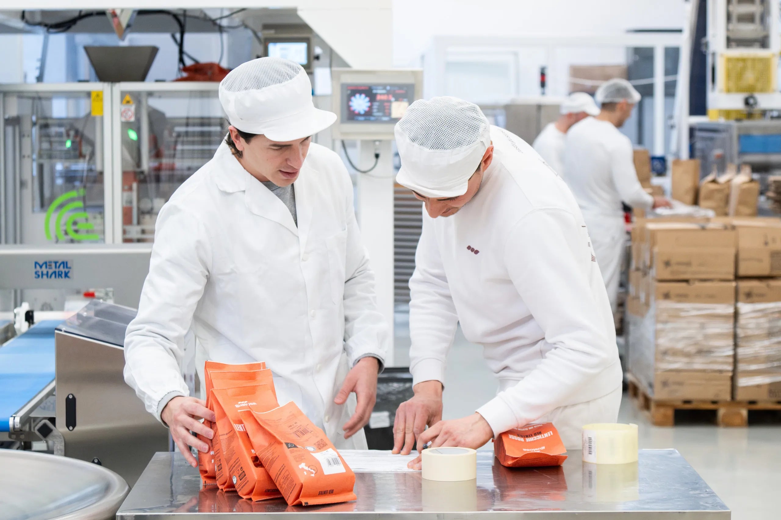 Due di noi preparano le confezioni di pasta di lenticchie rosse nel pastificio di Gravina in Puglia
