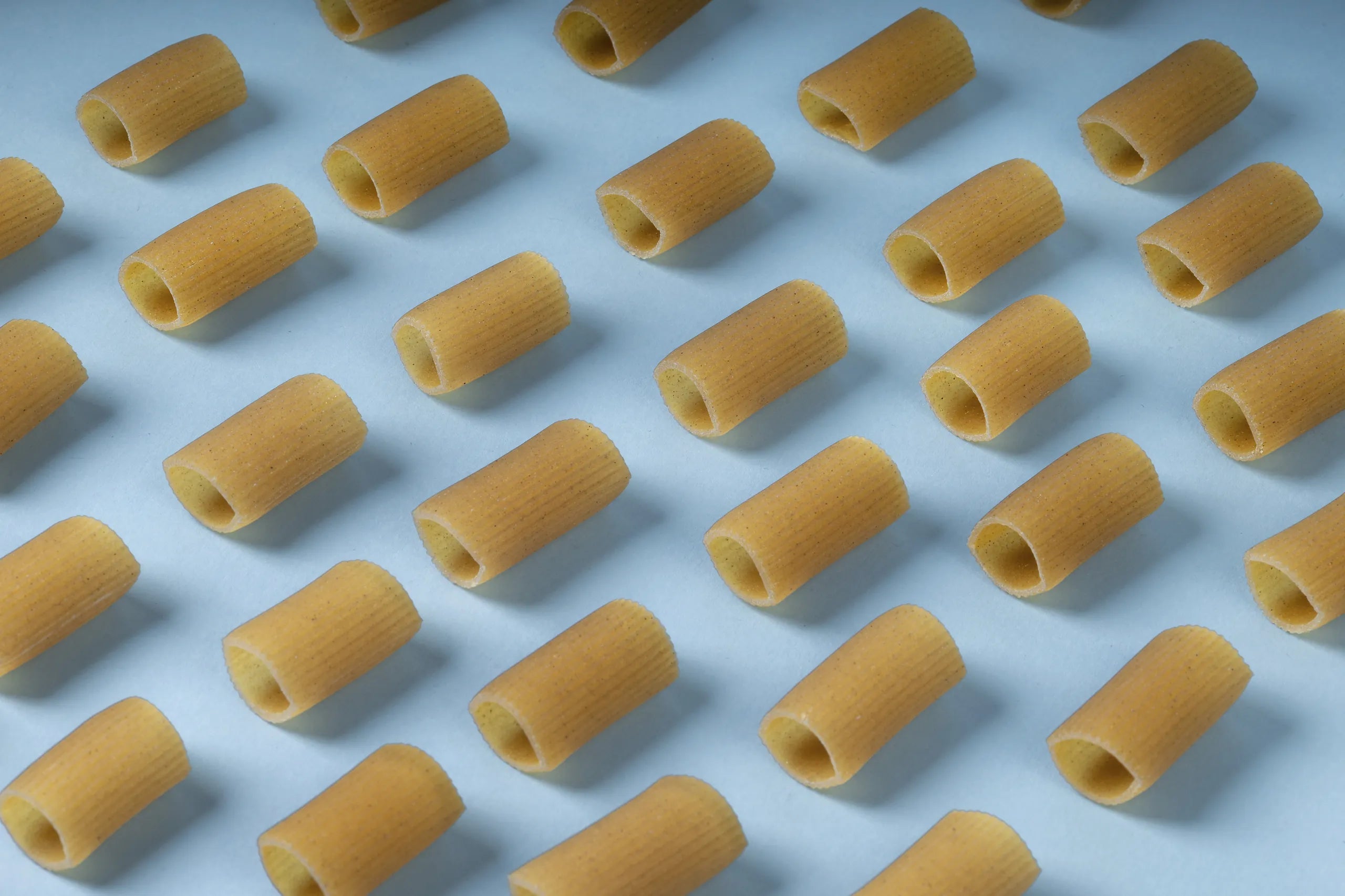 Rigatoni di pasta senza glutine su fondo azzurro