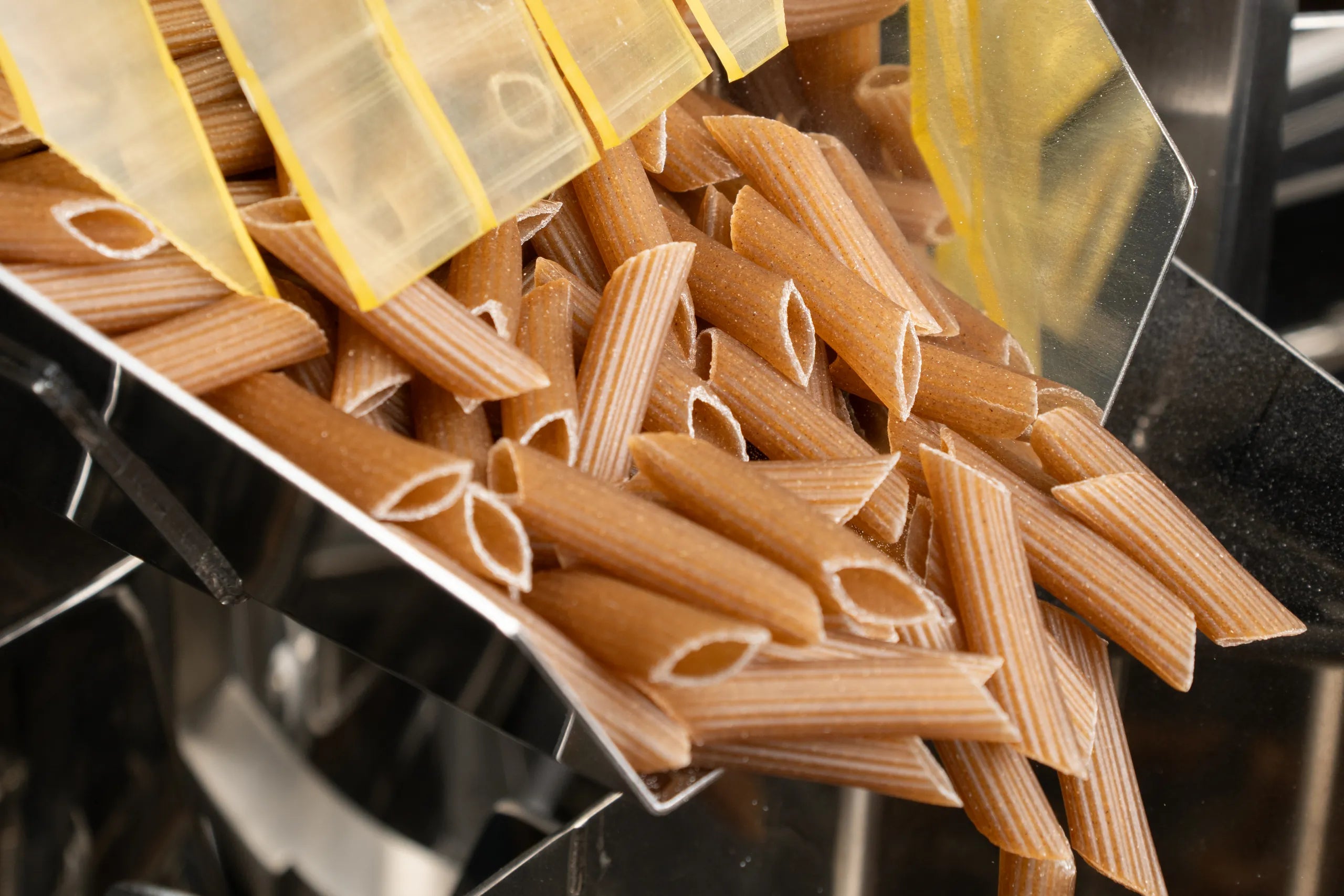 Penne senza glutine che scendono nella confezionatrice del pastificio Pasta Gustosa